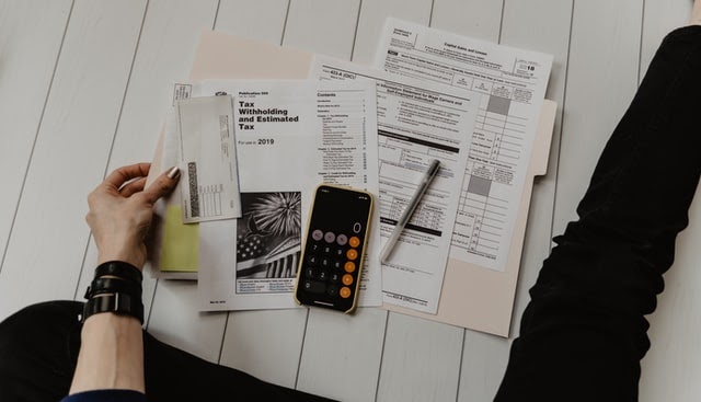 An overhead view of tax forms on a white floor.