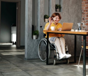 A person in a wheelchair at a table on a laptop.